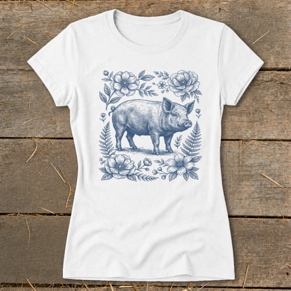 White t-shirt featuring a blue ink drawing of a piglet surrounded by flowers and ferns.