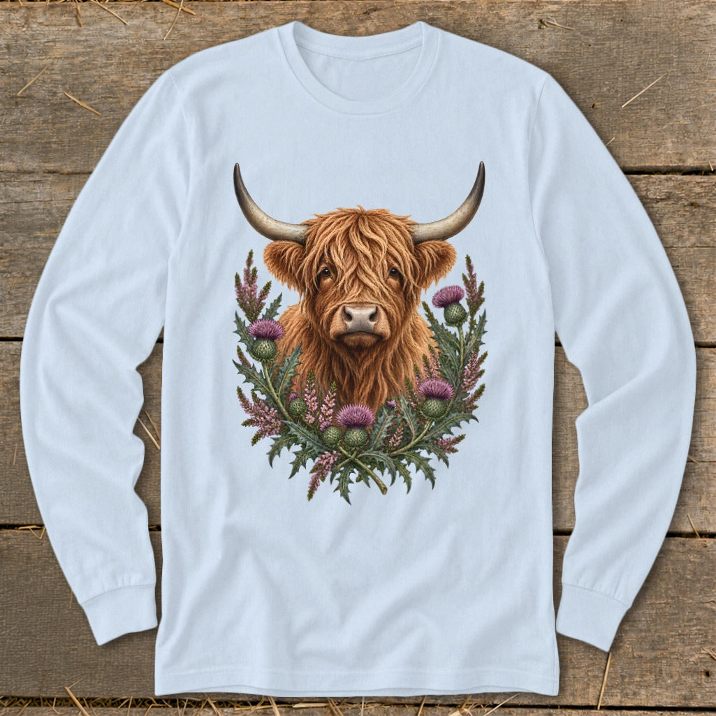 Highland cow with thistle wreath on a light blue long-sleeved shirt.