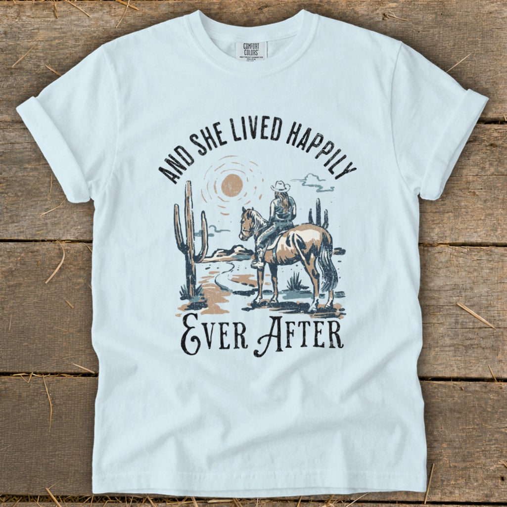 T-shirt with desert scene: woman on horse, cacti, and text "And She Lived Happily Ever After".
