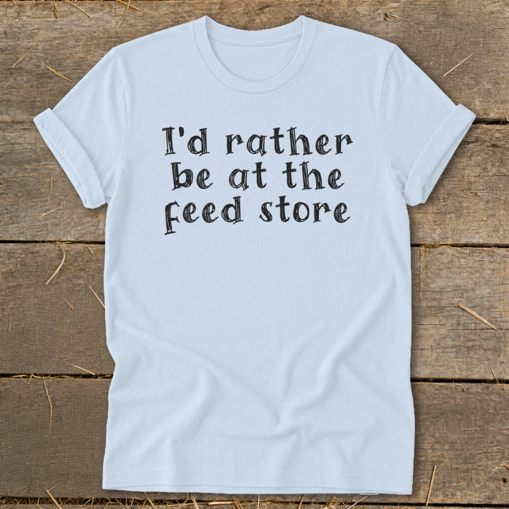 Light blue t-shirt with black text that reads "I'd rather be at the feed store."