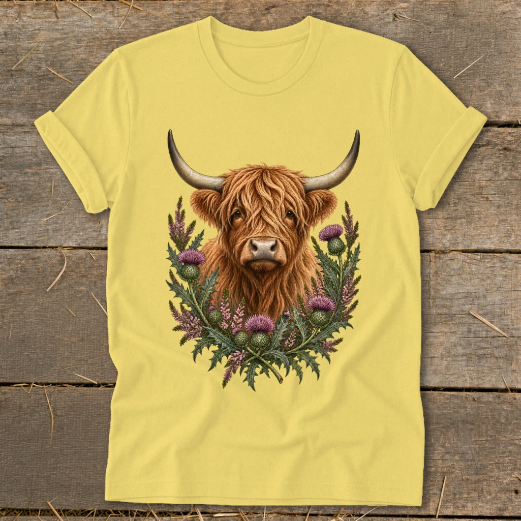 Highland cow with horns surrounded by purple thistles and greenery on a yellow t-shirt.