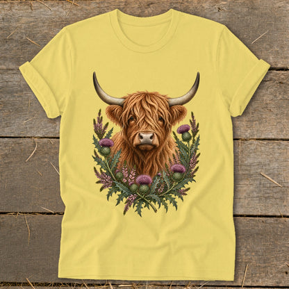 Highland cow with horns surrounded by purple thistles and greenery on a yellow t-shirt.