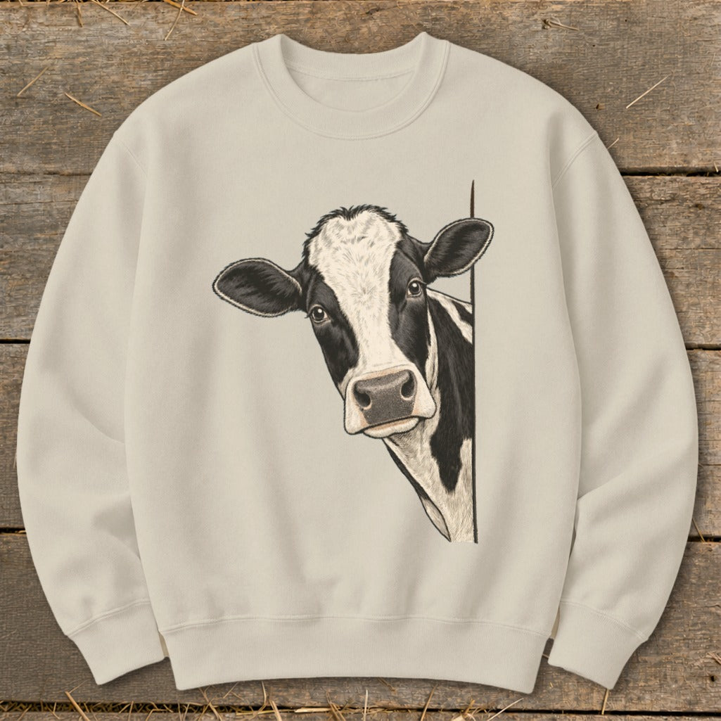 Black and white cow peeking from the side on a cream colored sweatshirt.