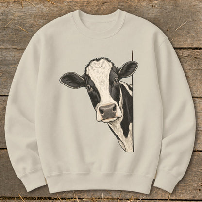 Black and white cow peeking from the side on a cream colored sweatshirt.
