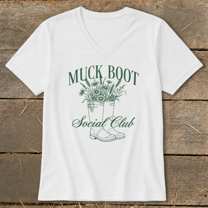 White t-shirt with green text and illustration of muck boots and flowers.
