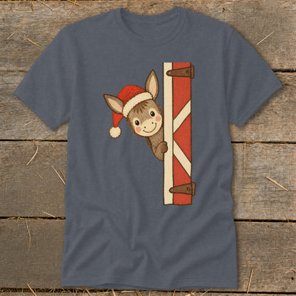 Donkey in Santa hat peeking from behind a red barn door on a blue shirt.