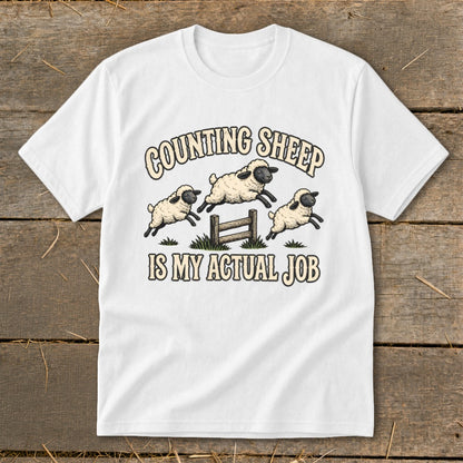 White t-shirt with "Counting Sheep Is My Actual Job" text and jumping sheep graphic.