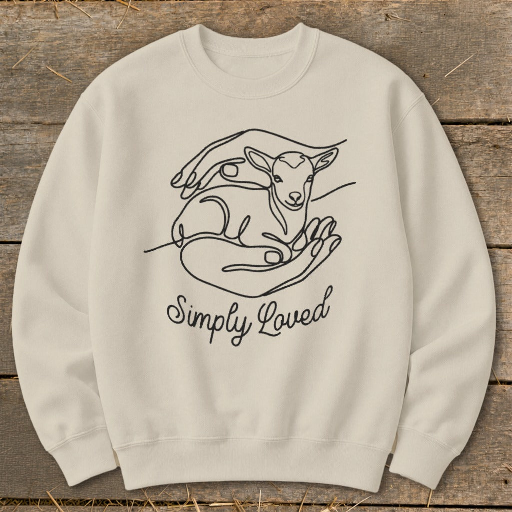 Cream sweatshirt with black line art of hands cradling a lamb and text "Simply Loved".