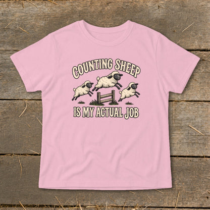 Pink t-shirt with "COUNTING SHEEP IS MY ACTUAL JOB" text and jumping sheep graphic.