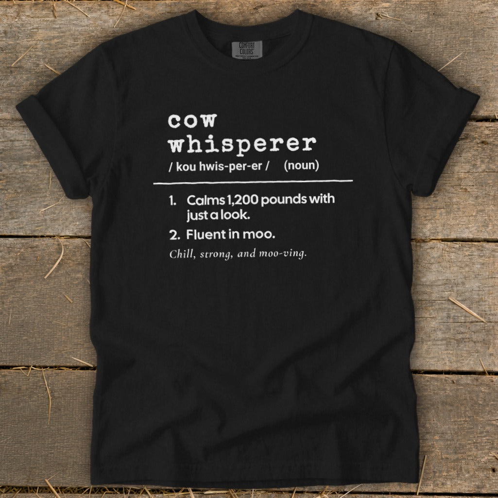 Black t-shirt with white text defining "cow whisperer" with humorous descriptions.