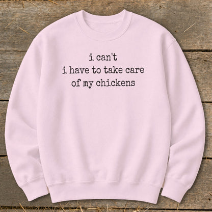 Pink crewneck sweatshirt with black text reading "i can't i have to take care of my chickens".