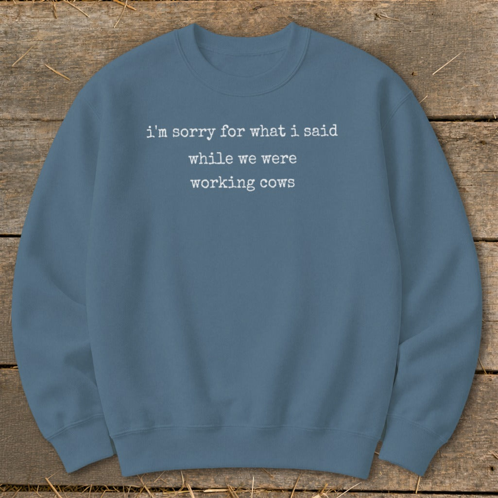 Blue sweatshirt with white text reading "i'm sorry for what i said while we were working cows."