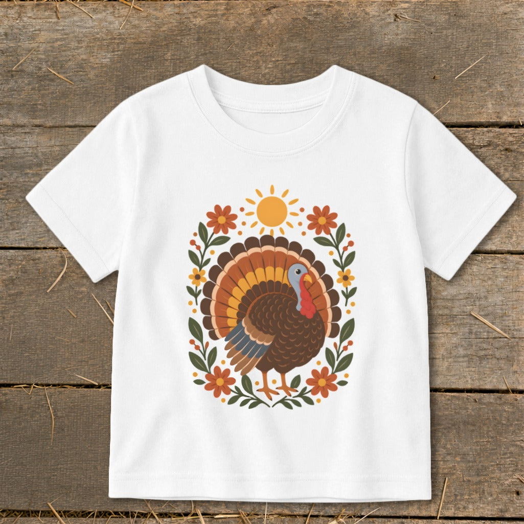 White t-shirt with a Thanksgiving turkey illustration surrounded by flowers and a sun.