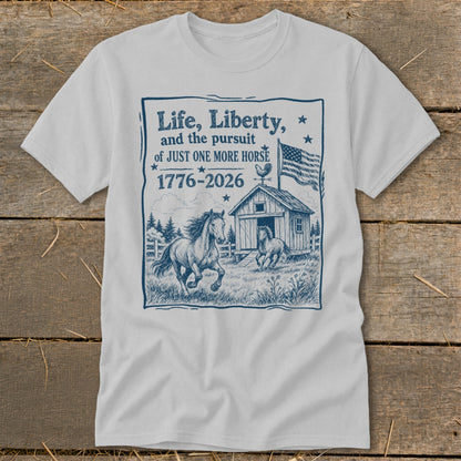 White t-shirt with blue graphic: "Life, Liberty, and the pursuit of JUST ONE MORE HORSE 1776-2026".
