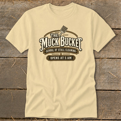 Khaki t-shirt with "The Muck Bucket School of Stall Cleaning Opens at 5 AM" text.