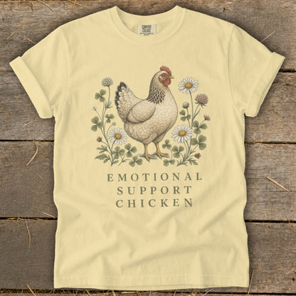 Pale yellow t-shirt with hen illustration and "Emotional Support Chicken" text.