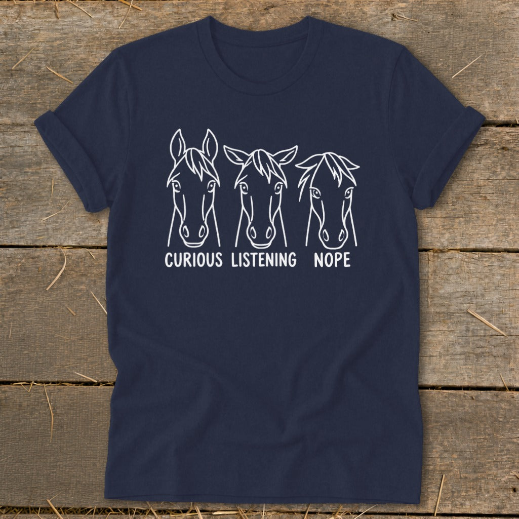 Dark blue t-shirt featuring a white line art graphic of three horse heads with the text "CURIOUS," "LISTENING," and "NOPE."