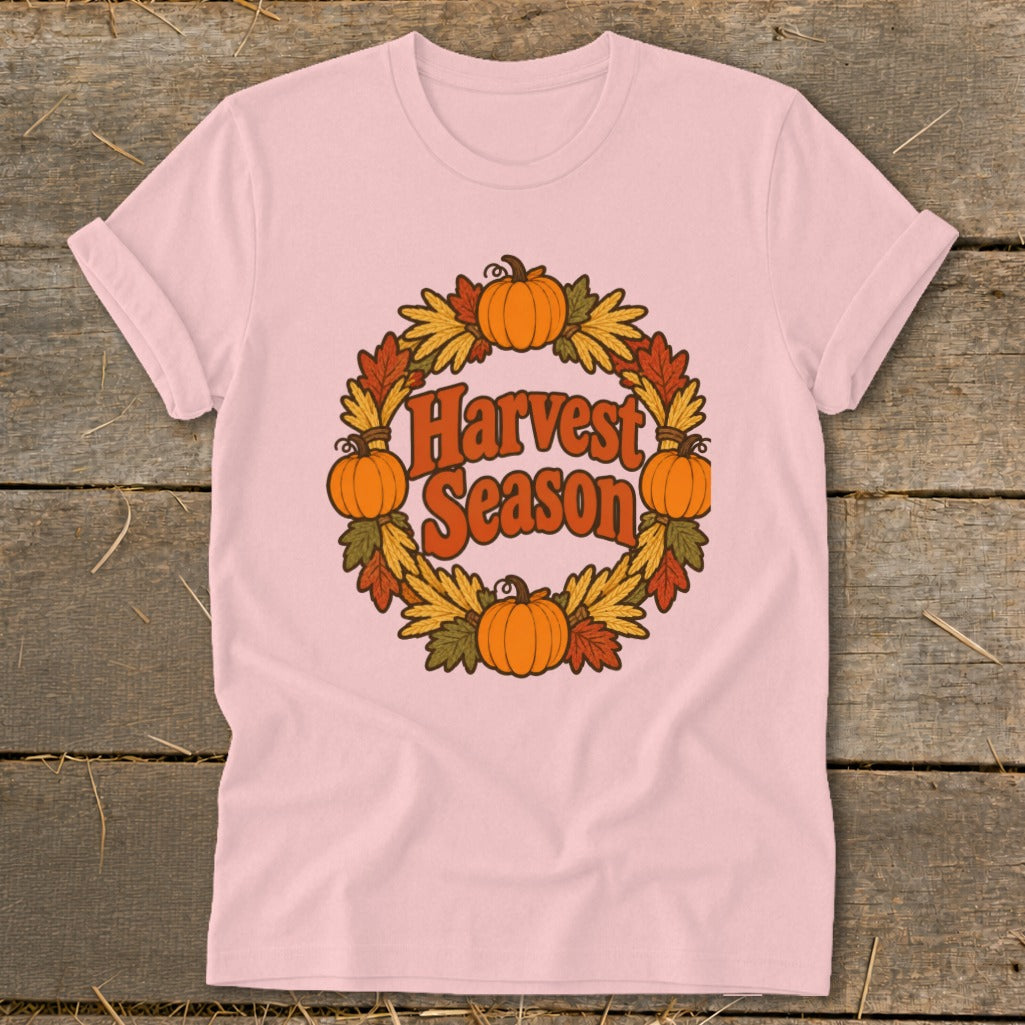 Pink t-shirt with "Harvest Season" text within a pumpkin and leaf wreath graphic.