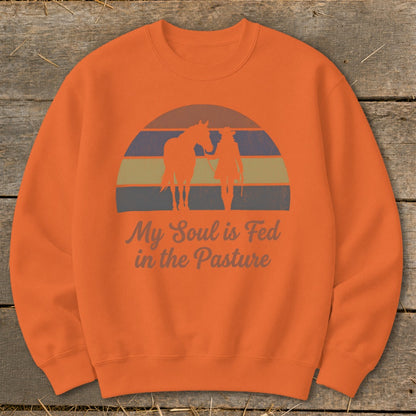 Orange sweatshirt with "My Soul is Fed in the Pasture" text and horse and rider silhouette.