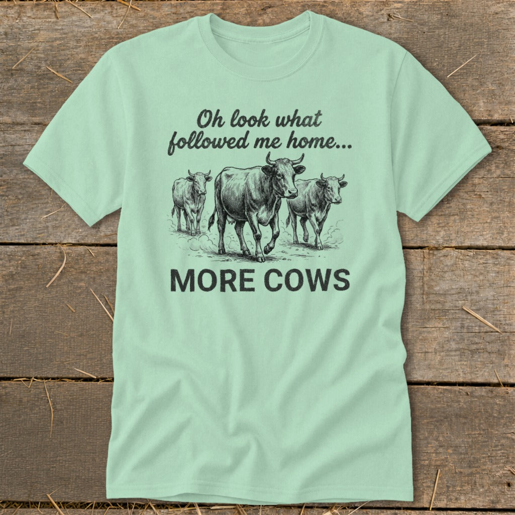 Mint green t-shirt with a sketch of three cows and text "Oh look what followed me home... MORE COWS".