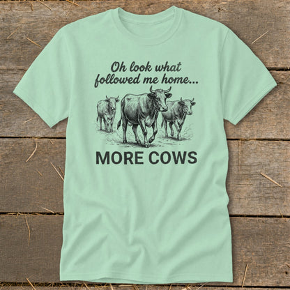 Mint green t-shirt with a sketch of three cows and text "Oh look what followed me home... MORE COWS".