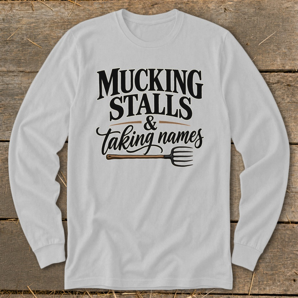 Long-sleeve shirt with "Mucking Stalls & Taking Names" and a pitchfork graphic.