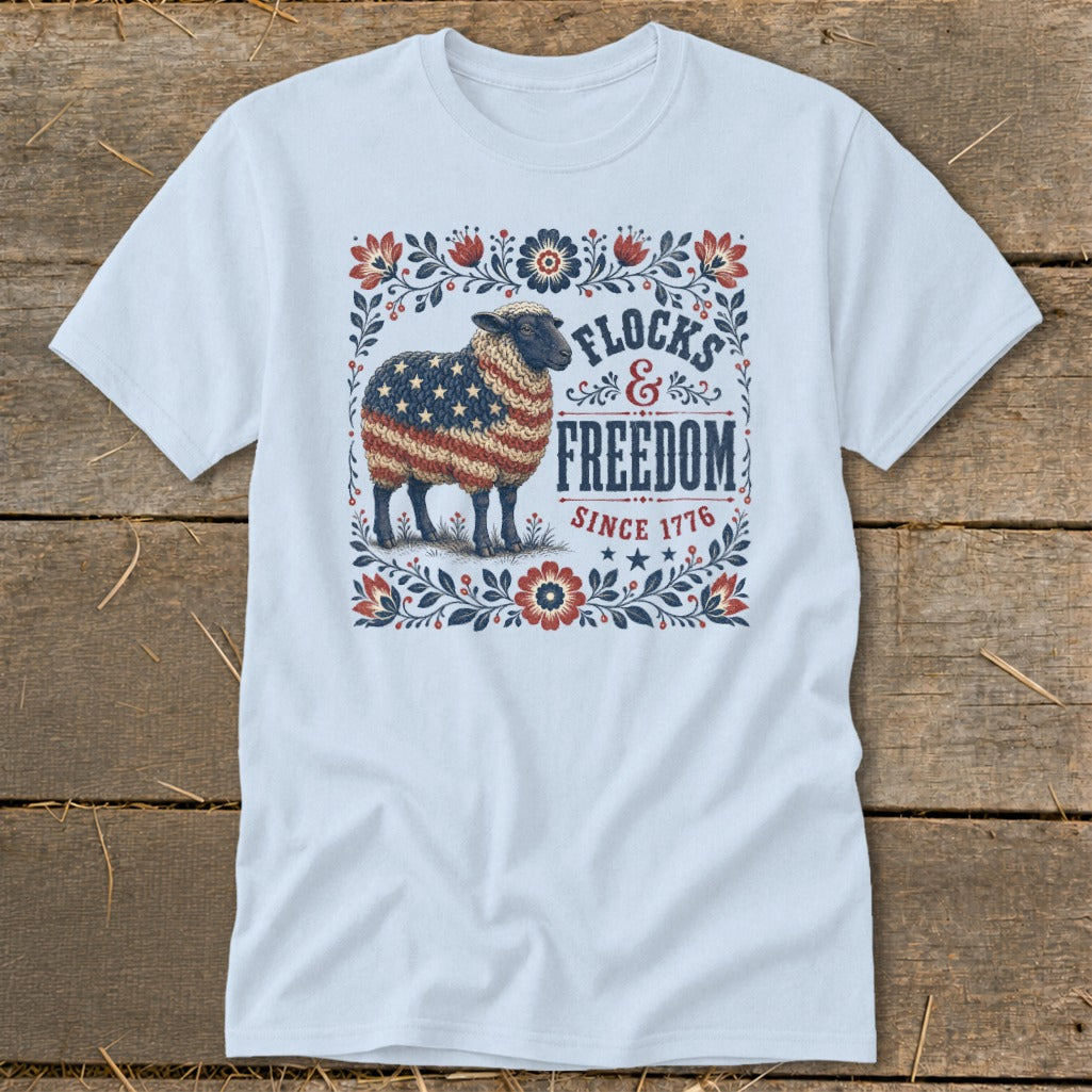 White t-shirt with a sheep graphic patterned with the American flag and the words "Flocks & Freedom Since 1776".