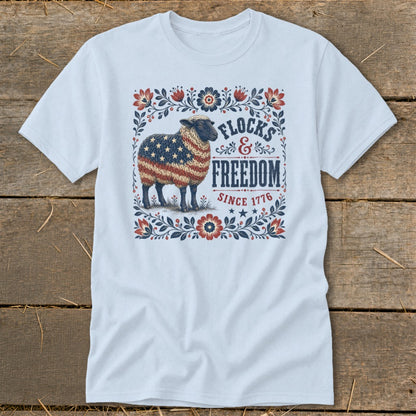 White t-shirt with a sheep graphic patterned with the American flag and the words "Flocks & Freedom Since 1776".