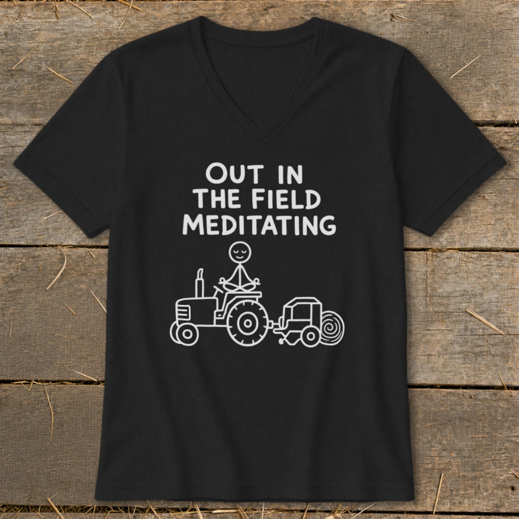Black t-shirt with "Out in the Field Meditating" text and stick figure on tractor.