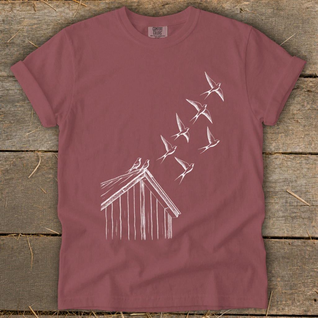 Dusty mauve crewneck t-shirt featuring a white line drawing of birds flying from a barn roof.