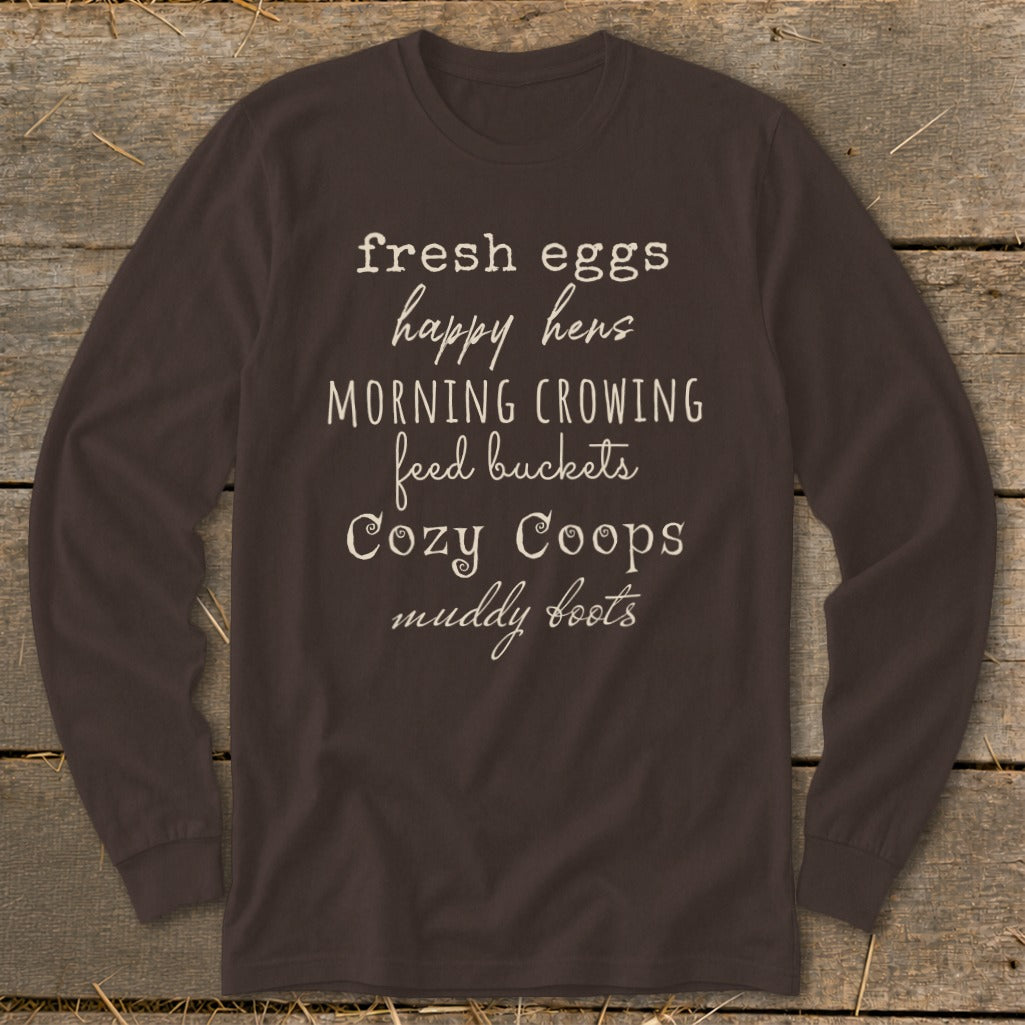 Brown long sleeve shirt with text: fresh eggs, happy hens, morning crowing, feed buckets, cozy coops, muddy boots.
