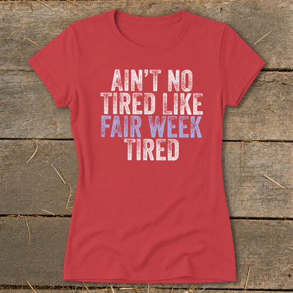 Red t-shirt with white and blue text that reads "Ain't no tired like fair week tired."