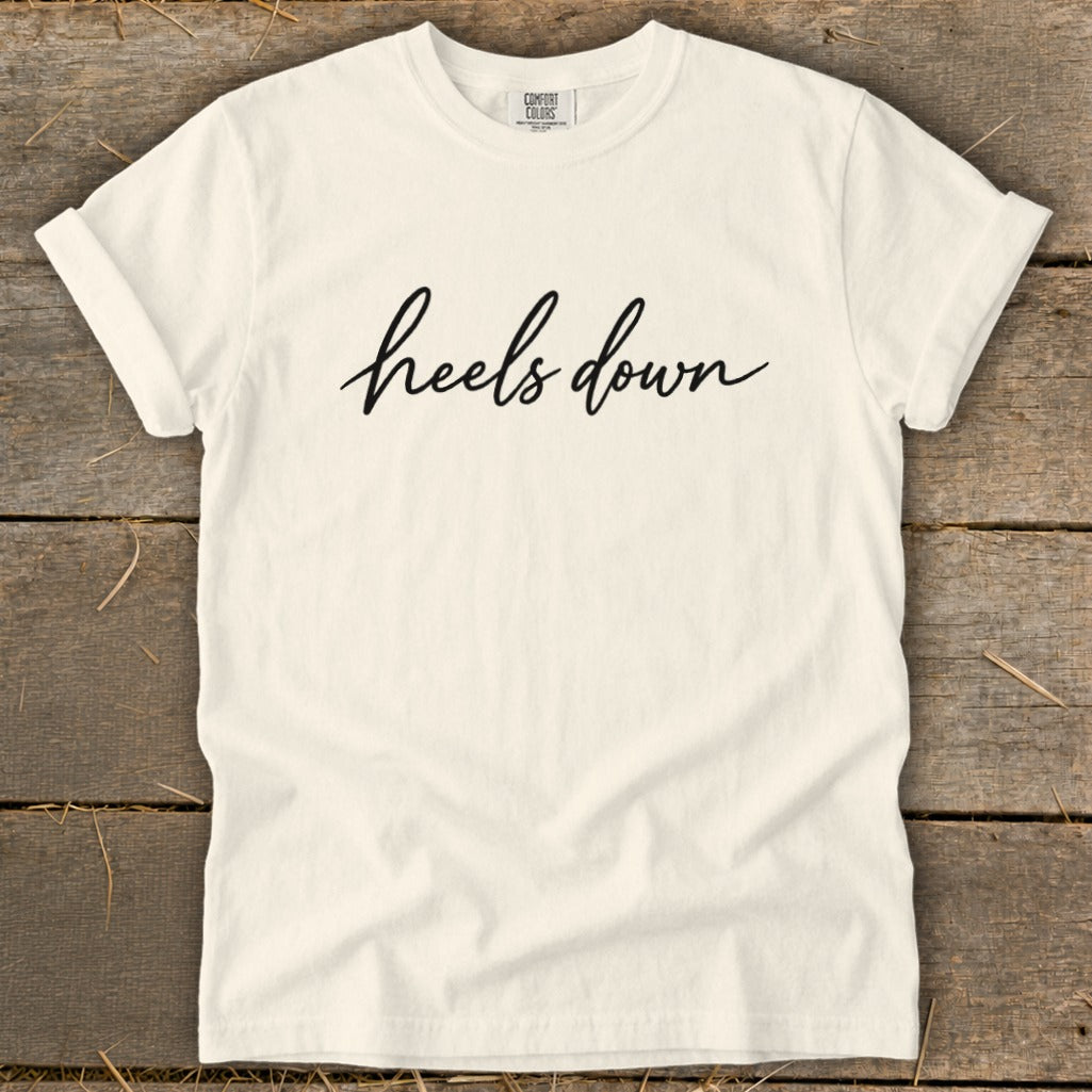 Cream t-shirt with black cursive text that reads "heels down."