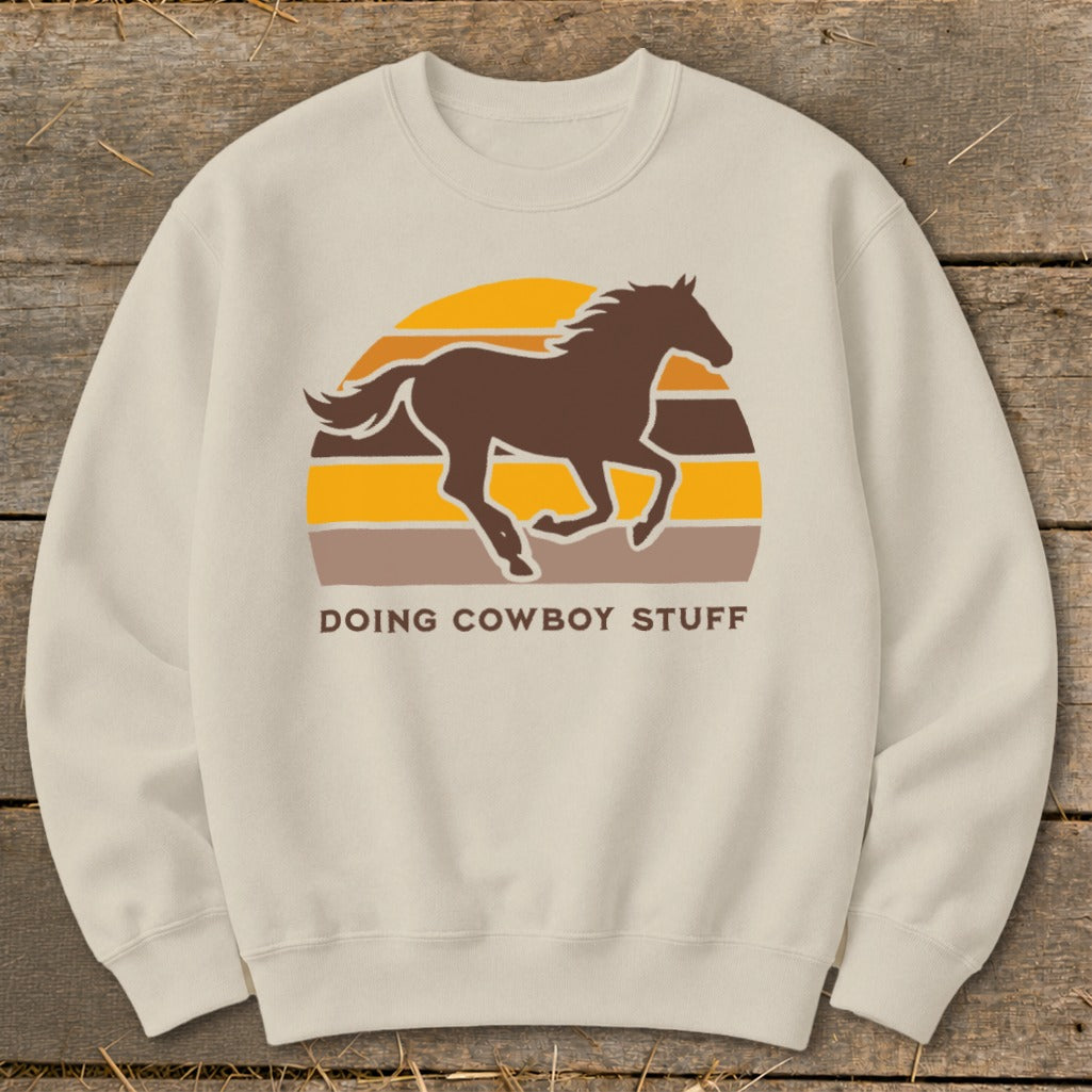 Beige crewneck sweatshirt with a brown horse silhouette over a retro sunset graphic and text.