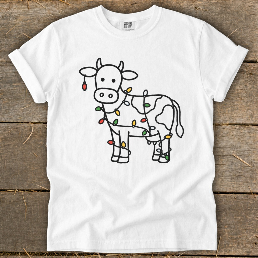White t-shirt with a line drawing of a cow decorated with colorful Christmas lights.