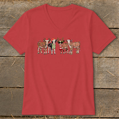 Five cartoon cows wearing Santa hats and Christmas lights are printed on a red t-shirt.