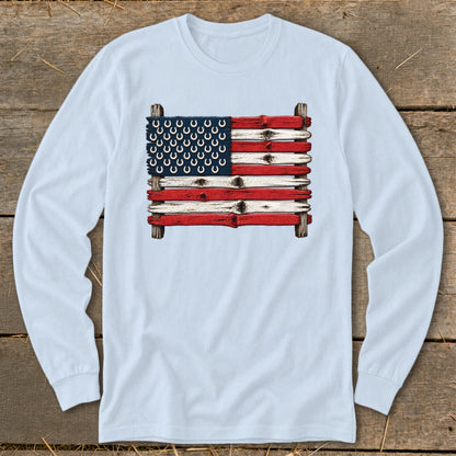 Light blue long-sleeve t-shirt featuring a graphic of the American flag made from weathered wooden planks and horseshoes.