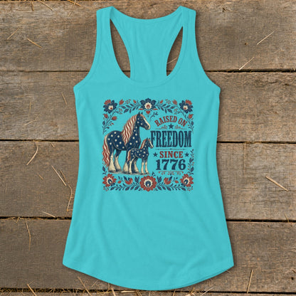 Turquoise tank top with horses and "Raised on Freedom Since 1776" text.