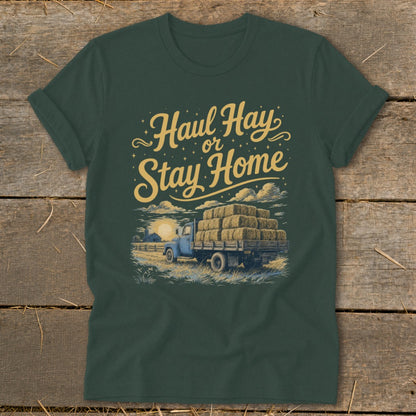 Green t-shirt with "Haul Hay or Stay Home" text and illustration of a blue truck loaded with hay bales.
