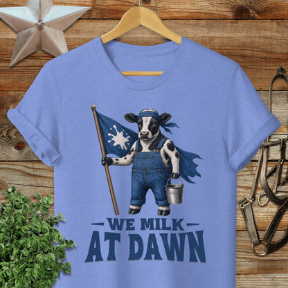 T-shirt with a cow character in overalls holding a flag, text reads "We Milk At Dawn".