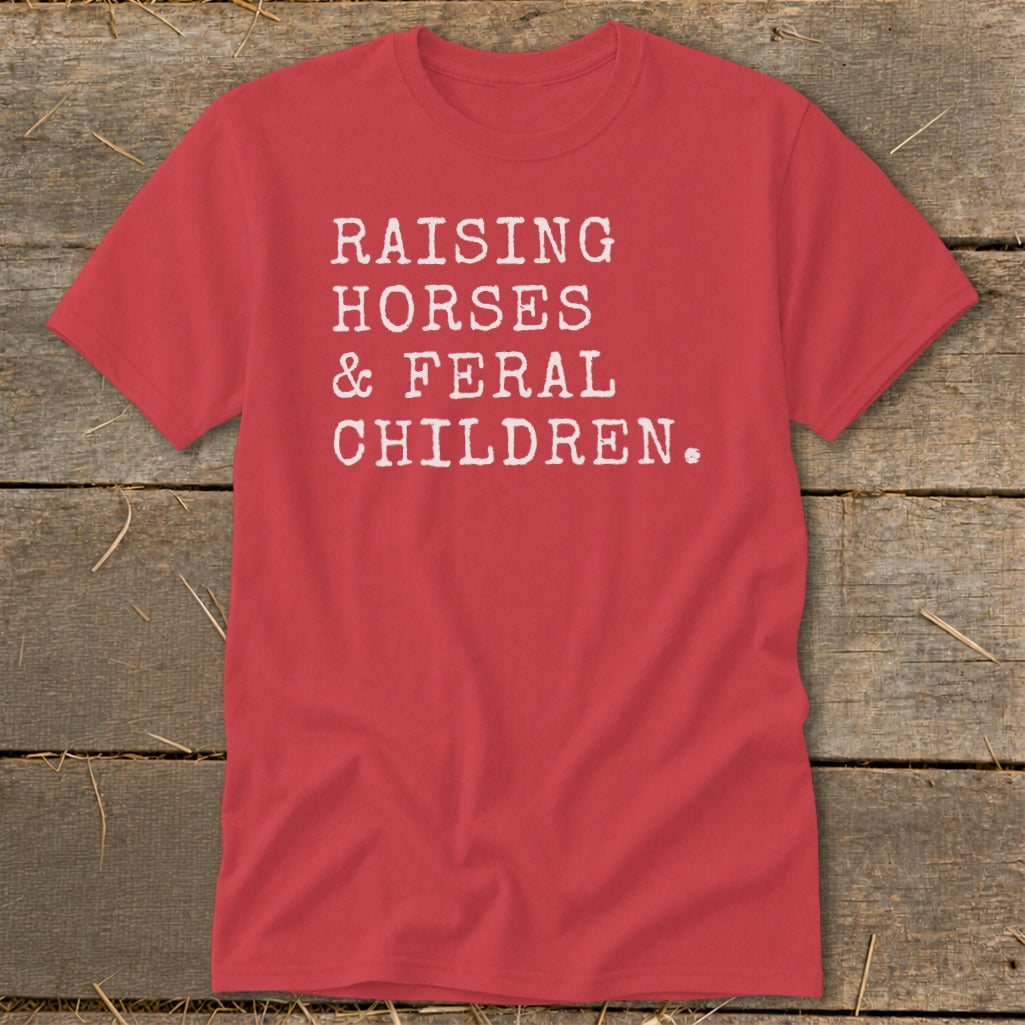Red t-shirt with white text reading "RAISING HORSES & FERAL CHILDREN."
