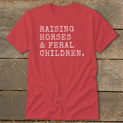 Red t-shirt with white text reading "RAISING HORSES & FERAL CHILDREN."