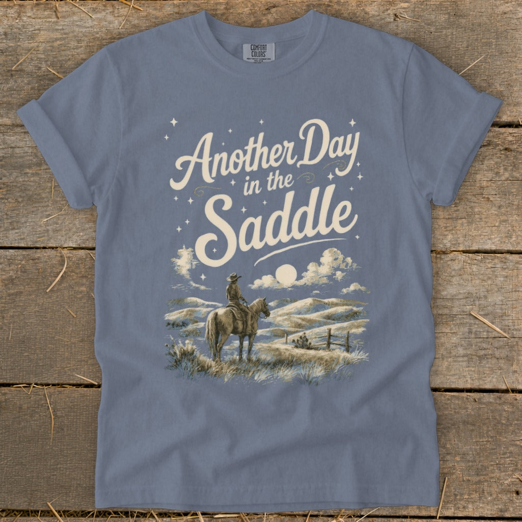 T-shirt graphic with "Another Day in the Saddle" text and cowboy on horseback illustration.