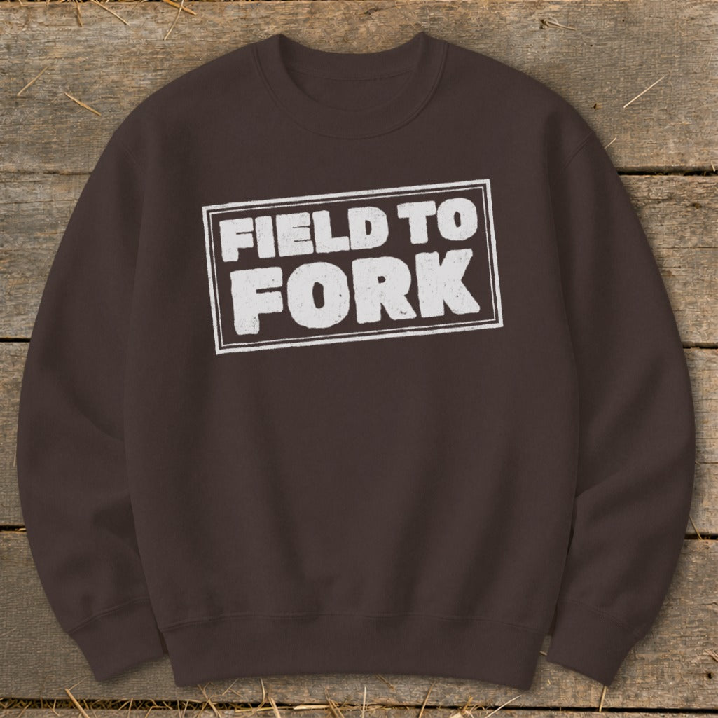 A brown crewneck sweatshirt featuring a distressed white rectangle with the text FIELD TO FORK.