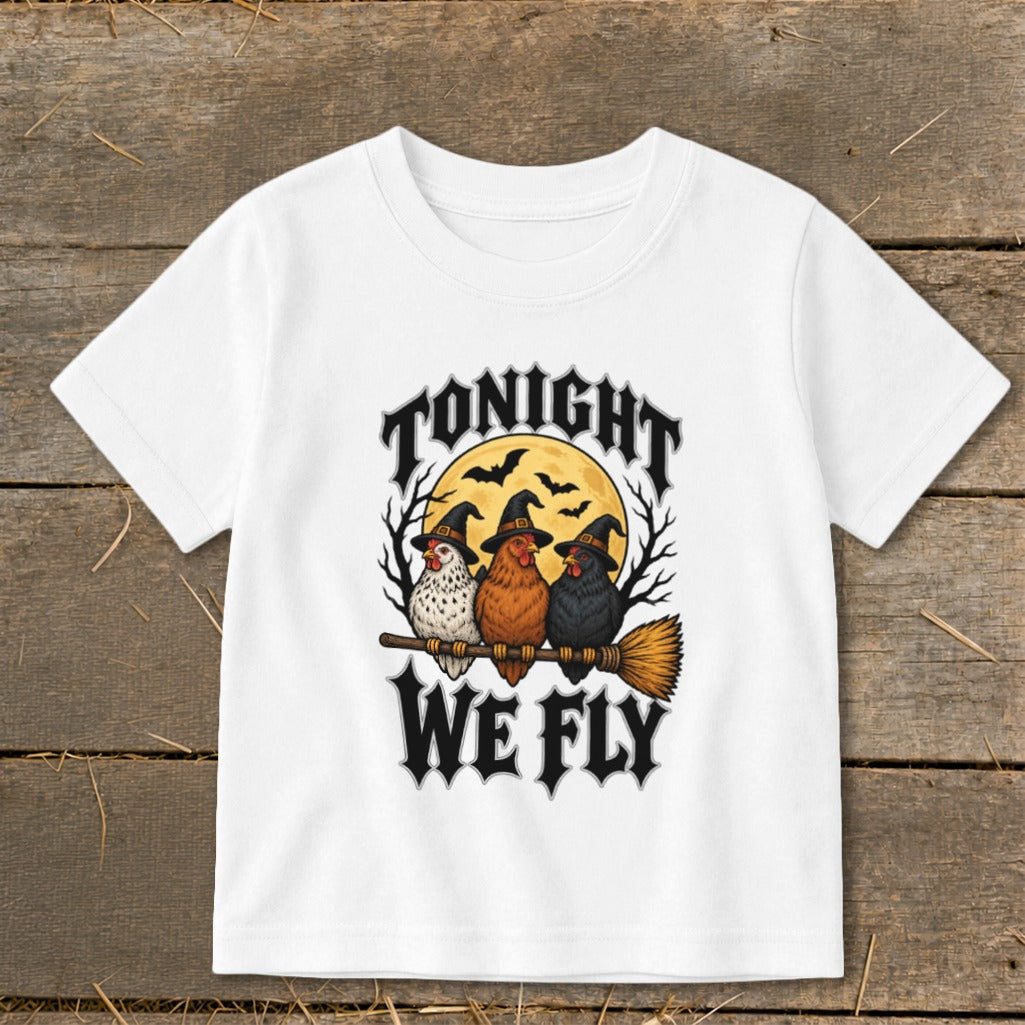 White t-shirt with three chickens in witch hats flying on a broomstick, text says "TONIGHT WE FLY".