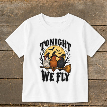 White t-shirt with three chickens in witch hats flying on a broomstick, text says "TONIGHT WE FLY".