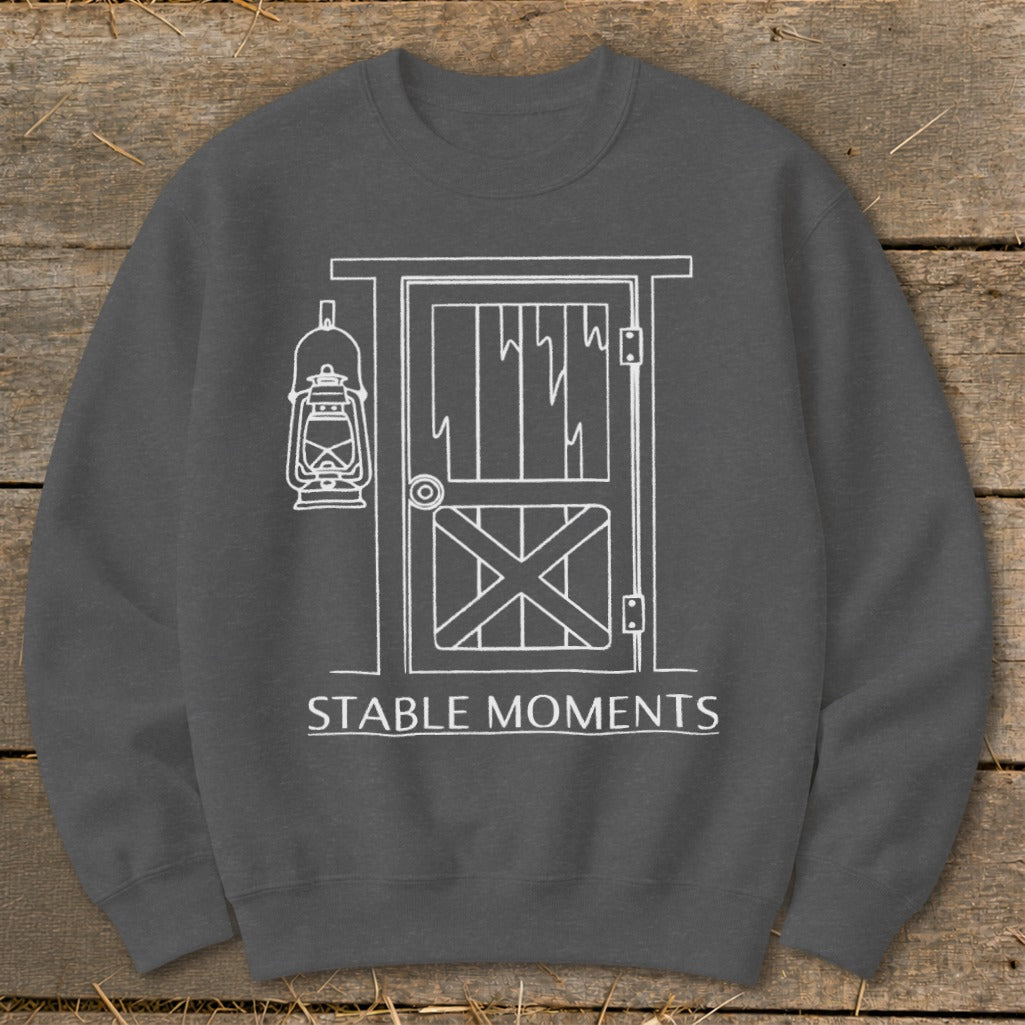 Dark gray sweatshirt with white line art of a barn door and lantern, text "STABLE MOMENTS".