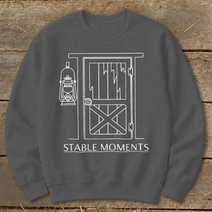 Dark gray sweatshirt with white line art of a barn door and lantern, text "STABLE MOMENTS".