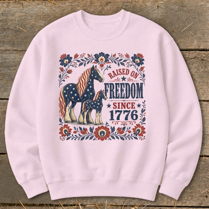 Pink sweatshirt with American flag horses and "Raised on Freedom Since 1776" text.