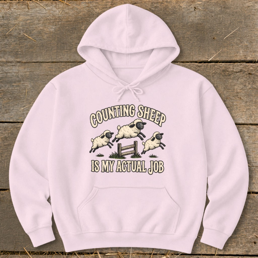 Light pink hoodie with "Counting Sheep Is My Actual Job" text and sheep graphic.
